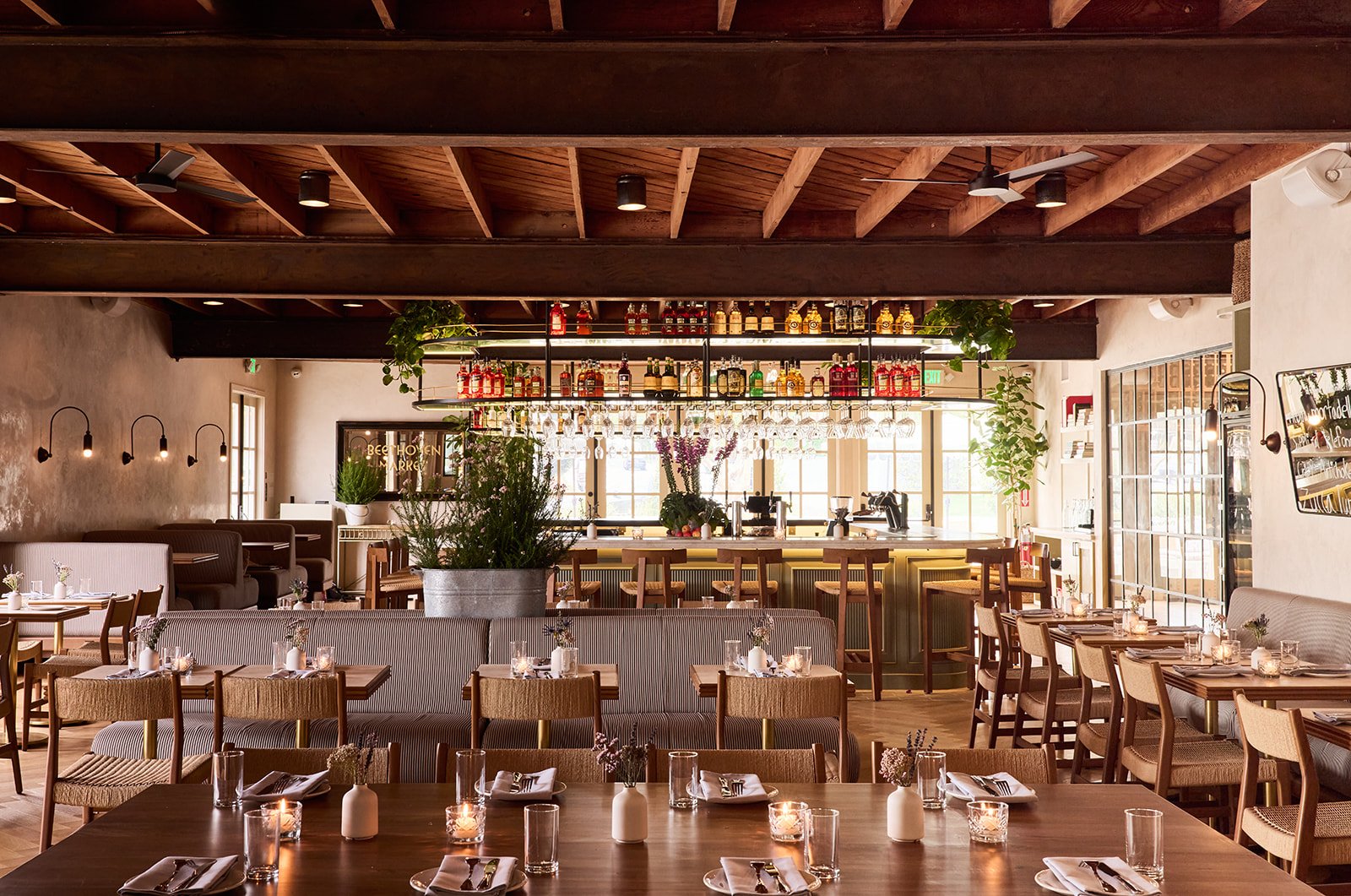Warm restaurant dining room with wood beams and set tables